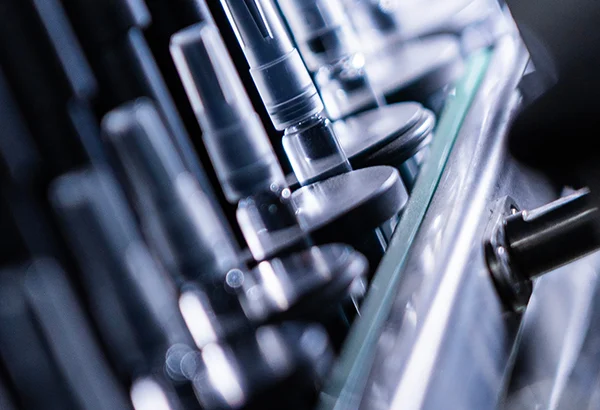 Macro close-up view of precision automated assembly machinery components on a pharmaceutical manufacturing line.