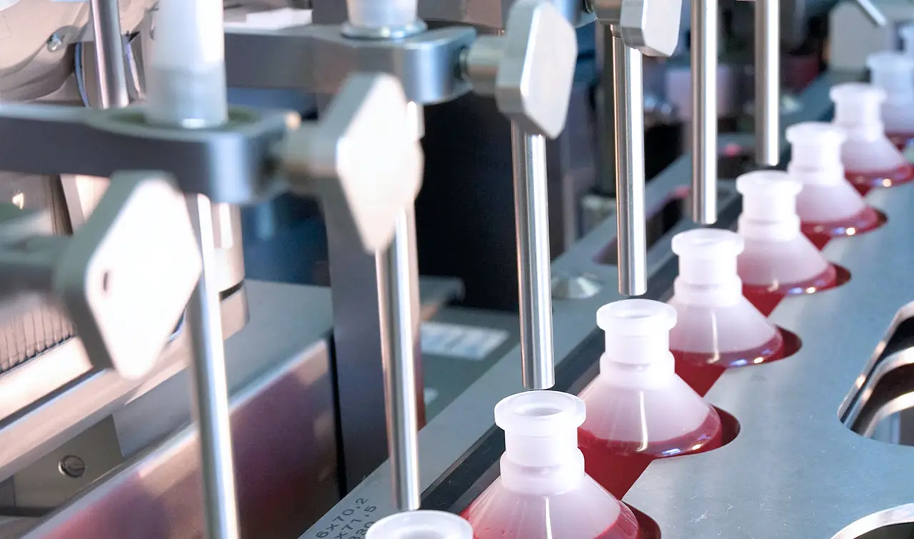 Automated filling line for oral liquid pharmaceutical products, showing bottles being filled with precision.