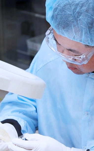 A lab technician performing a manual visual inspection in a sterile pharmaceutical cleanroom.