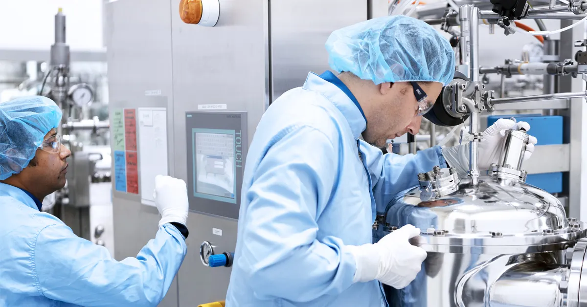 Specialist inspecting a stainless steel solution preparation tank for large-scale biologics and small molecule manufacturing.