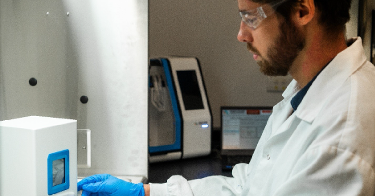 Laboratory scientist wearing protective eyewear and gloves operating equipment for lipid nanoparticle (LNP) formulation development and manufacturing.